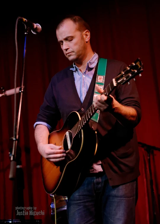 a man with a guitar on stage during a performance