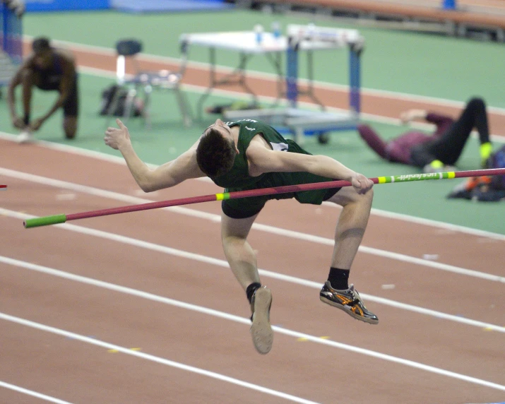 a person jumping above a hurdle on a running track