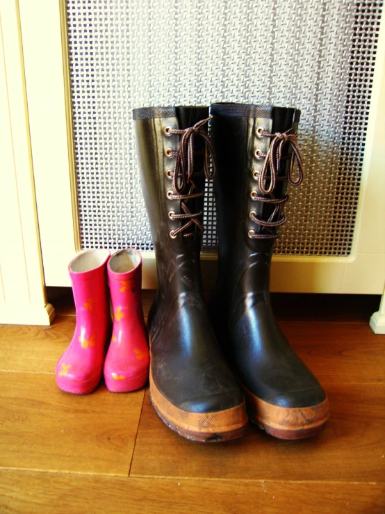 two pairs of boots are next to an electrical heater