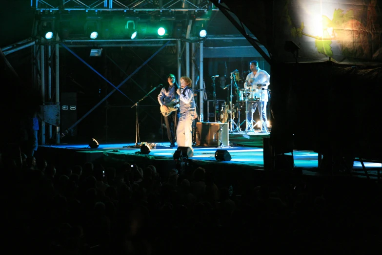 two people singing with microphones at night on stage