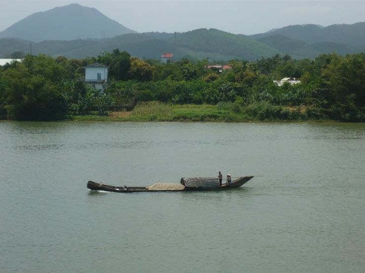 a man in a long boat with hills in the background