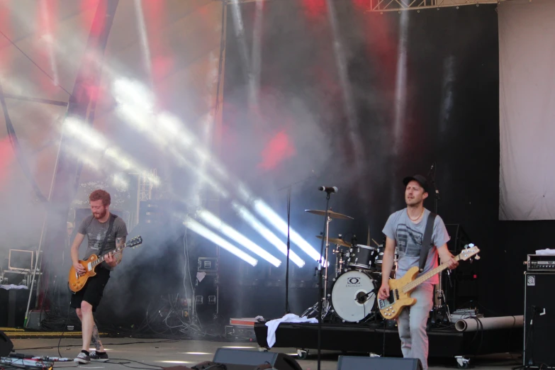 three men playing guitars on stage in front of a set of microphones