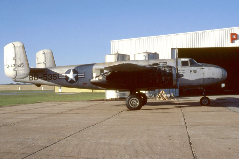 a old military style airplane in an open hangar