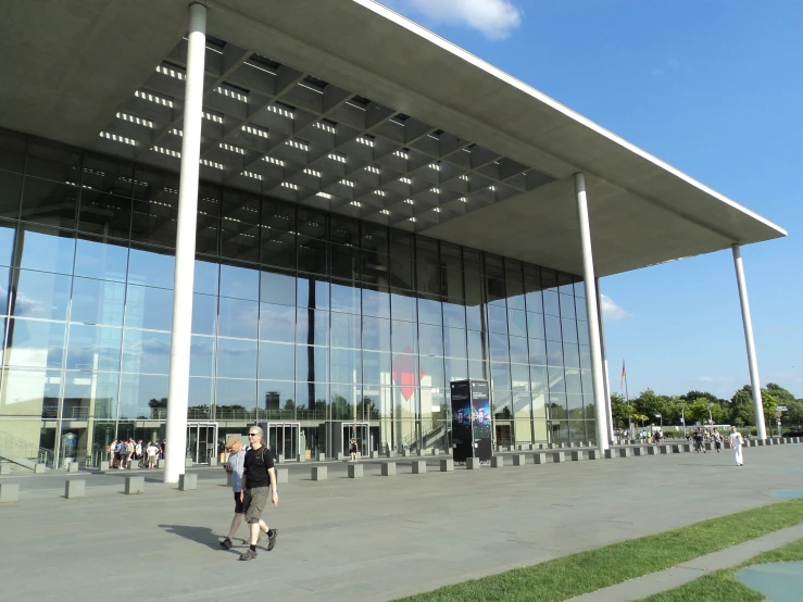 a man in black walking outside a large building