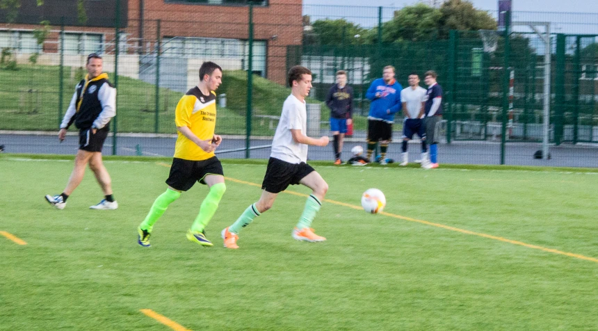 two men with yellow uniforms kicking a soccer ball