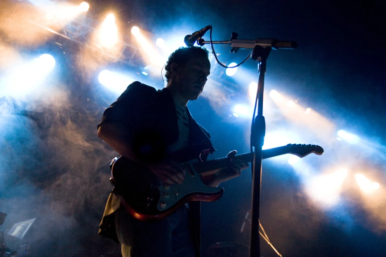 a guy plays his guitar under blue light