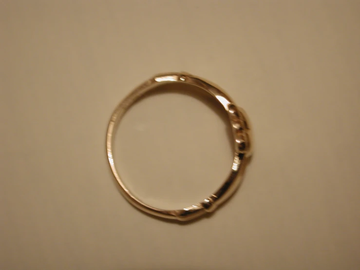 a plain gold wedding band on top of white table