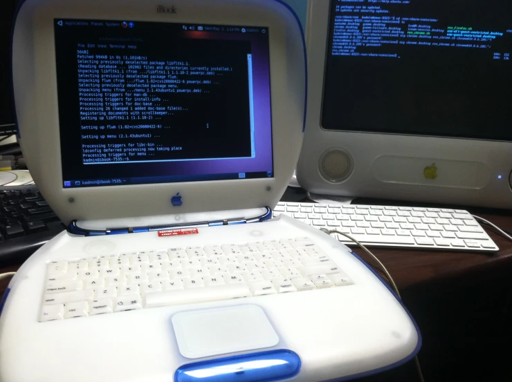 a macbook on a desk with keyboard and computer monitor