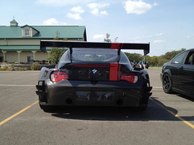 a black car sitting in a parking lot with red striped stripes