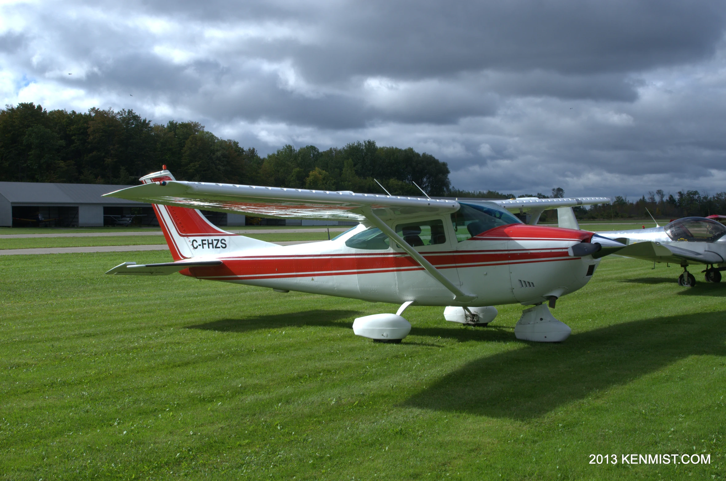 two small airplanes sit on the grass outside