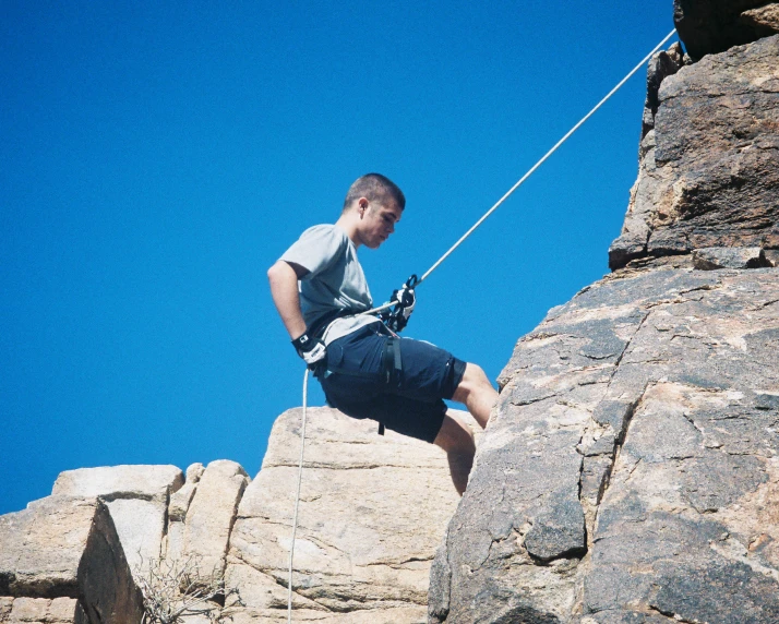 the man is climbing along a rope on the mountain