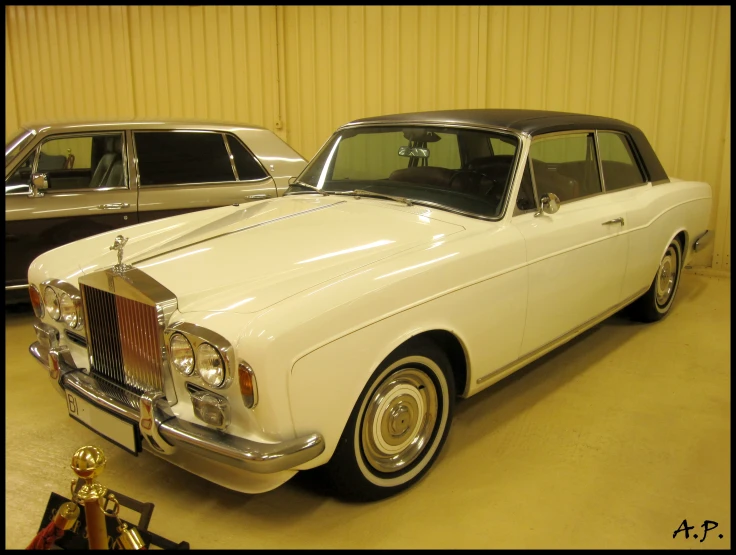 two old fashion cars in a garage next to each other