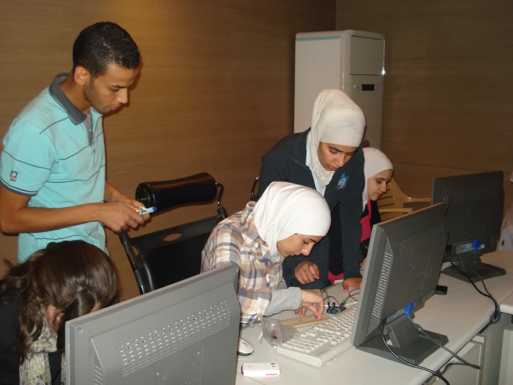 people in a room and looking at pictures on computer monitors