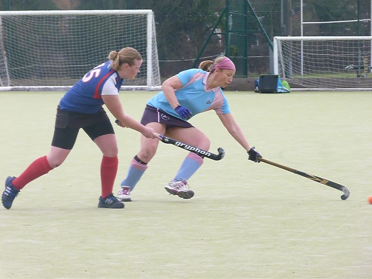 a couple of women are playing hockey on a field