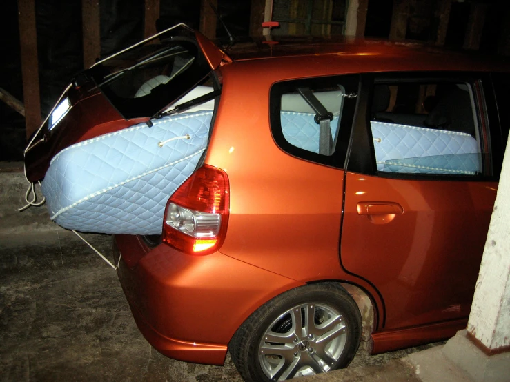 an orange car with a mattress on top