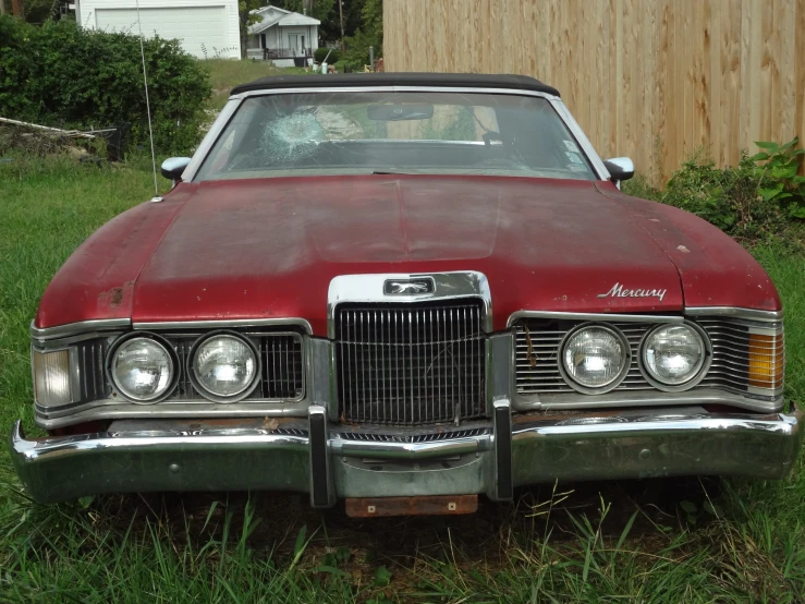 an old red car sitting on the grass