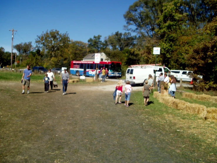 people in grassy field near multiple vehicles and a camper