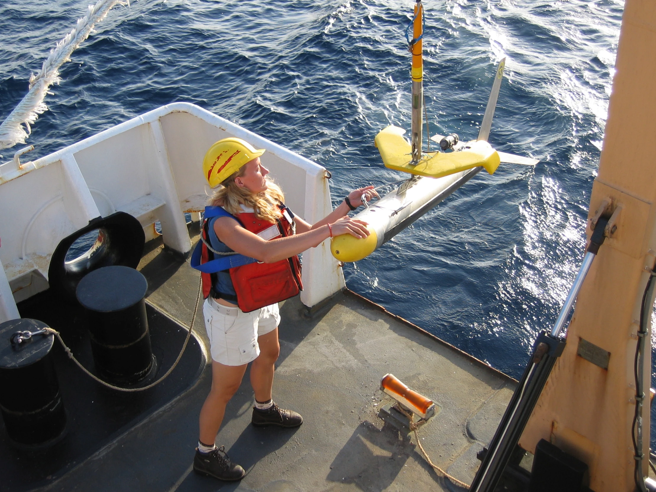 a person in yellow hardhat holding onto soing in the ocean