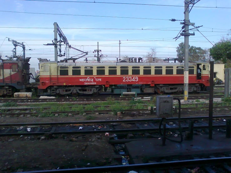 a red and yellow train traveling past a group of power lines