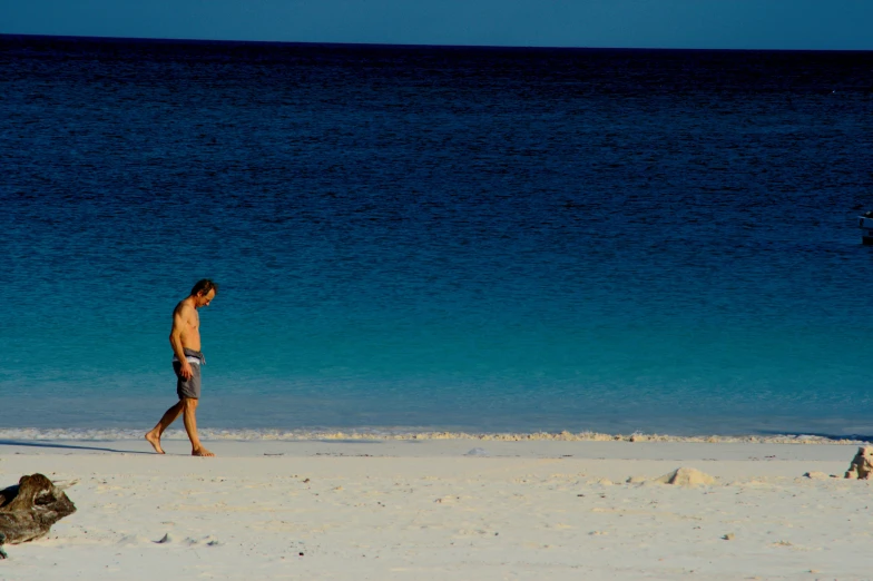 a person walks along a beach with water in the background