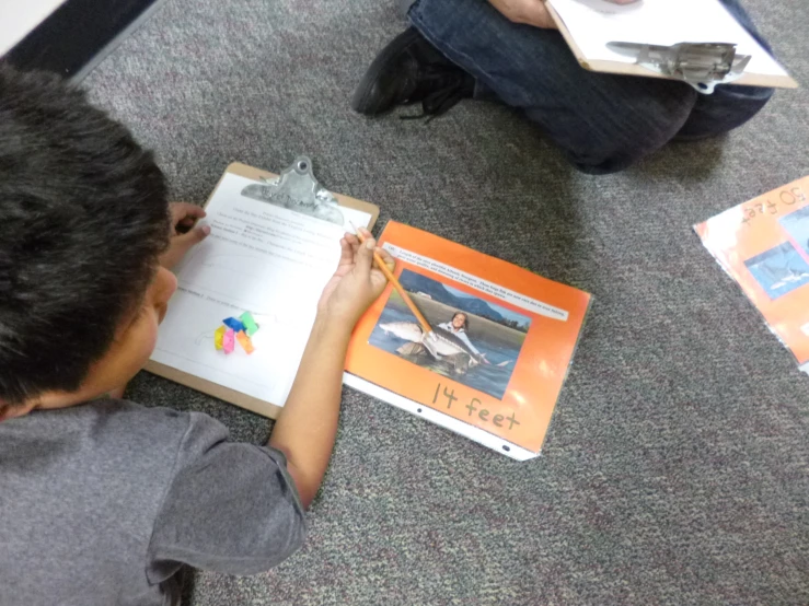 boy sitting on the floor doing homework in front of his book