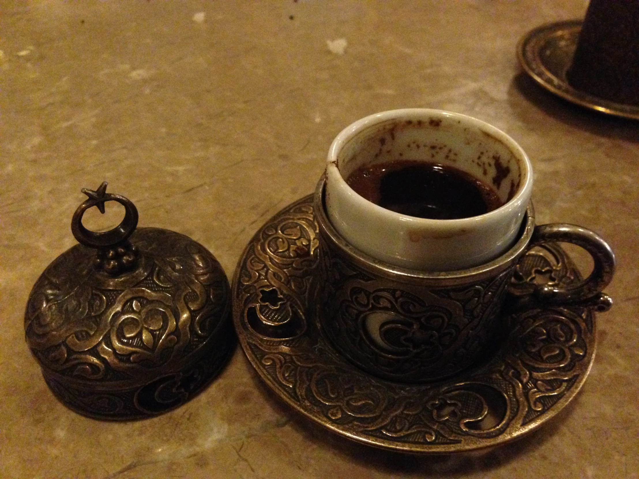 a cup of coffee and an ornate lid on a plate