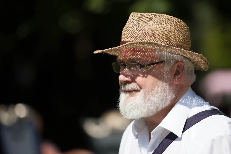 a older man with a long white beard wearing a straw hat and striped tie