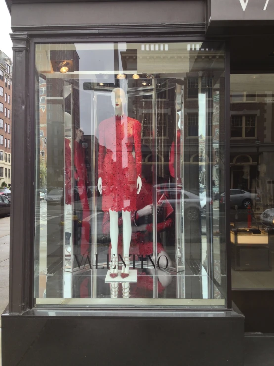 the red and white mannequin is behind glass windows