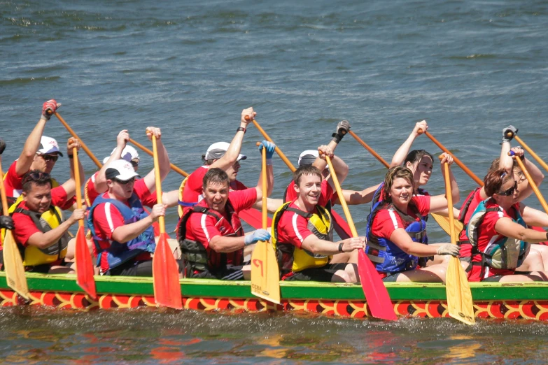 a group of people wearing red shirts are in a boat with paddles