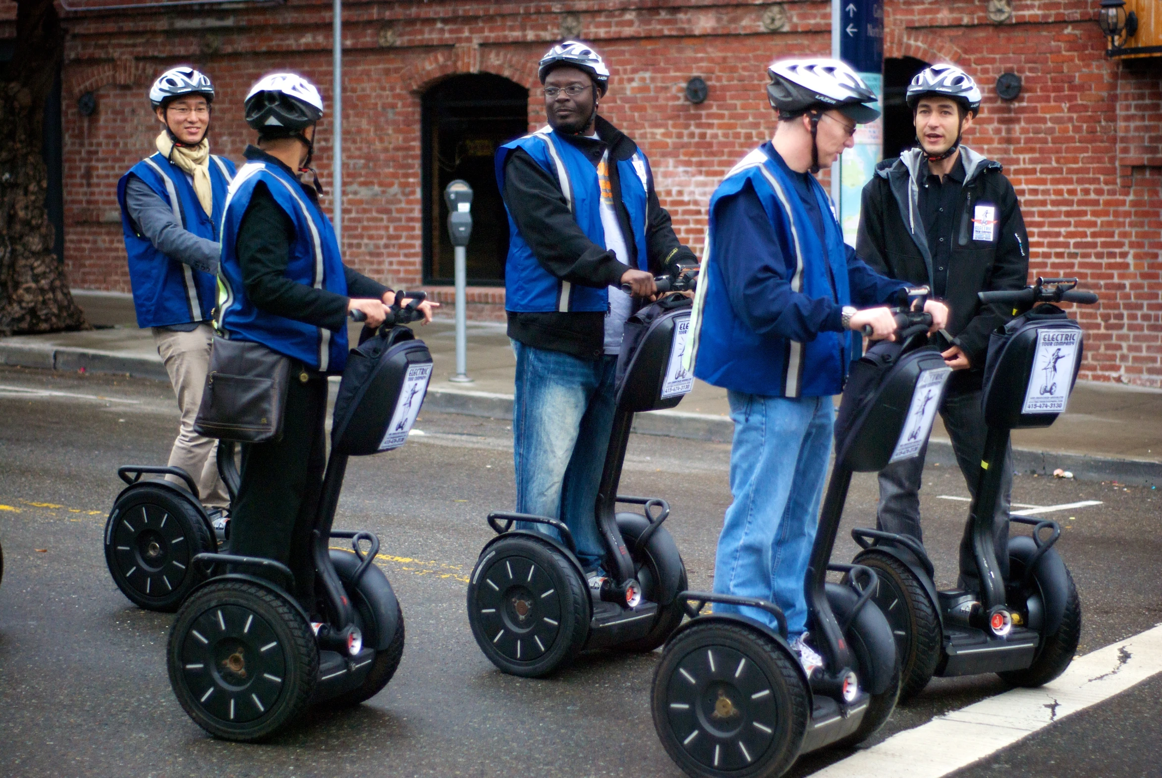 a group of guys with helmets and their luggage using some sort of two wheeled vehicles