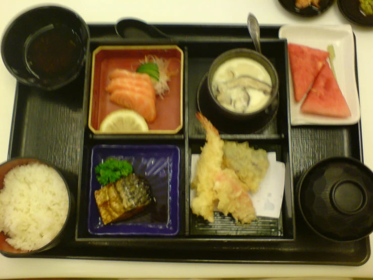 a tray of different sushi dishes, including watermelon and salmon