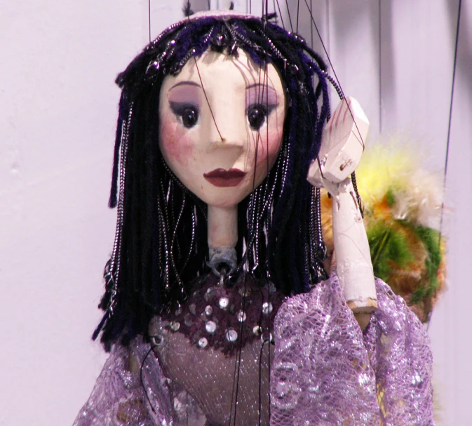 an unusual doll is holding her head in one hand and wearing a purple outfit on one