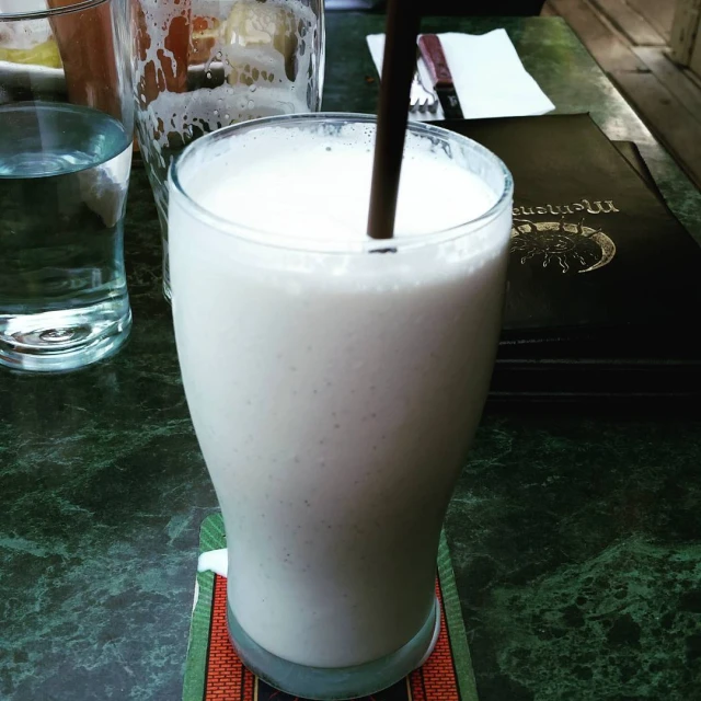 a glass with liquid sitting on a table next to a book