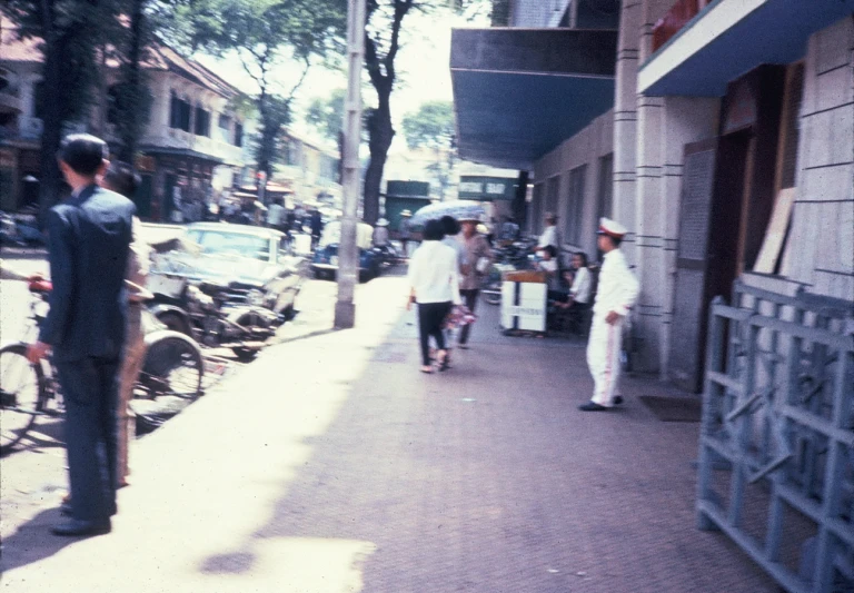 people walk along a sidewalk next to bicycles