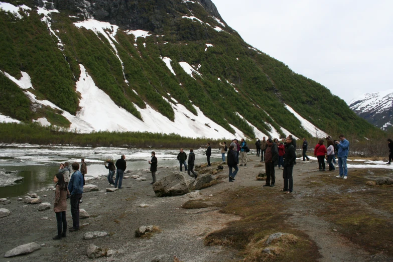 a group of people walking by a snowy mountain