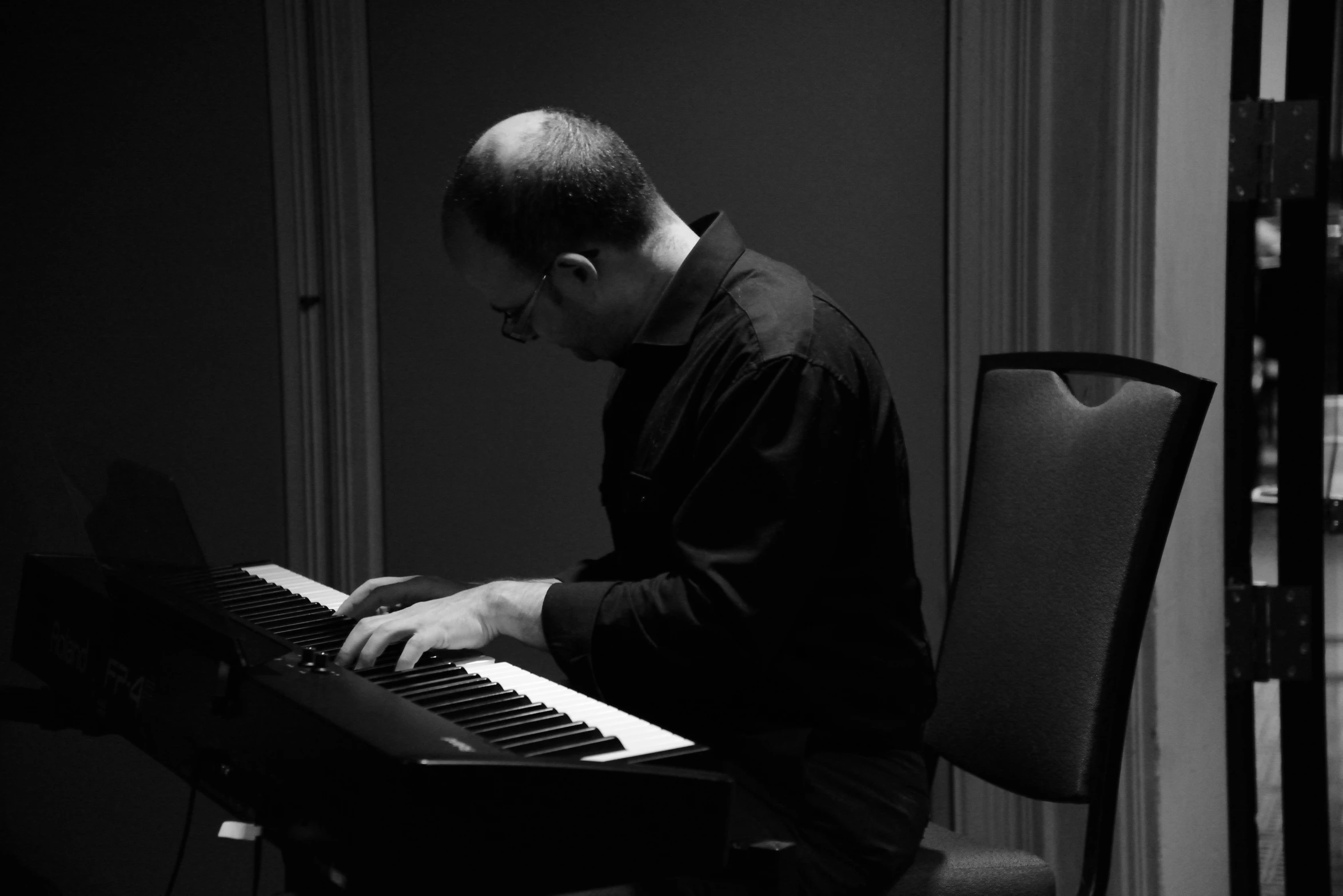 a man is playing an electronic keyboard in a room