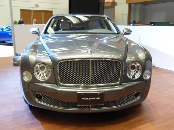 silver sport car parked in a showroom next to another sports car