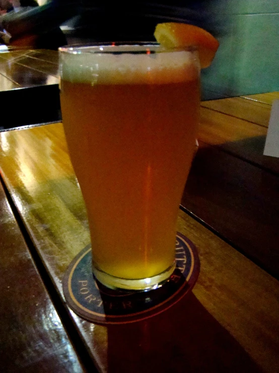 a pint of beer sits on a bar counter