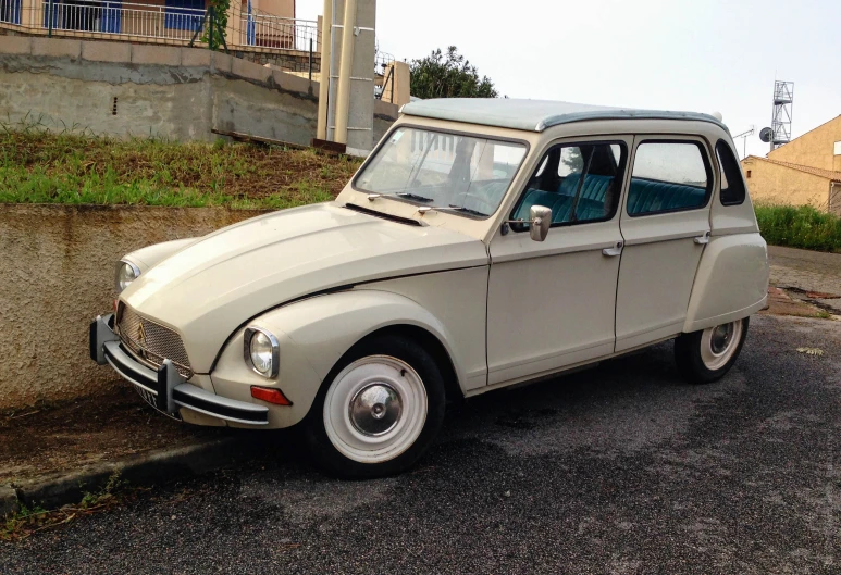 an old fashioned beige car parked on the side of the street