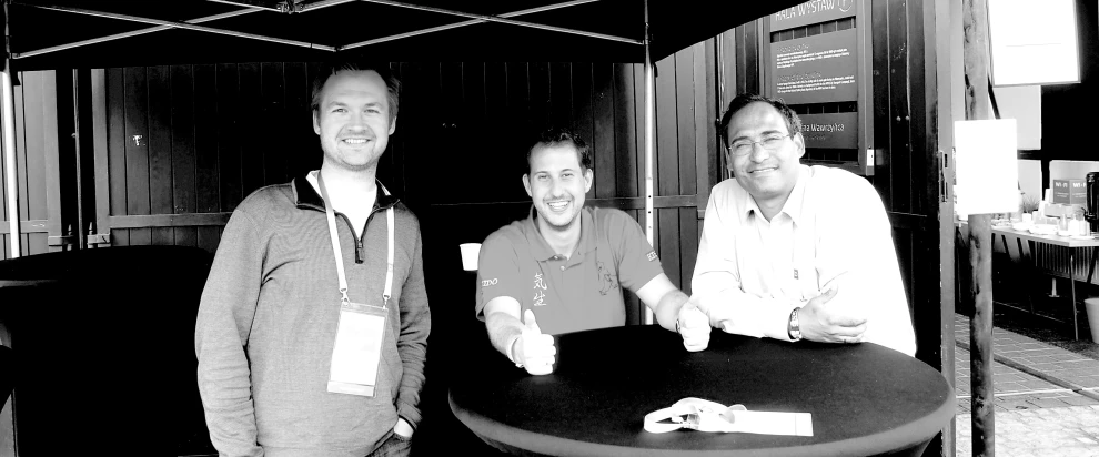 a group of three men sitting at a black and white table