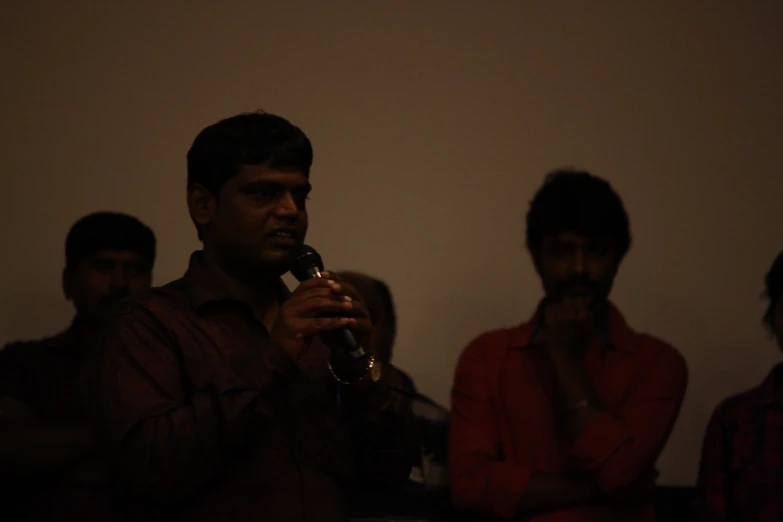 men sitting around in a dimly lit room