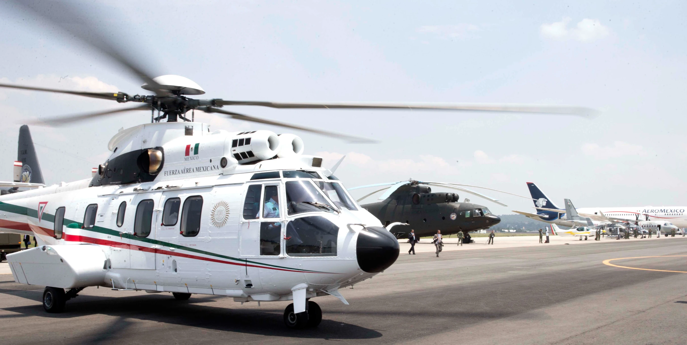 a helicopter on an airport runway with a man in the cockpit