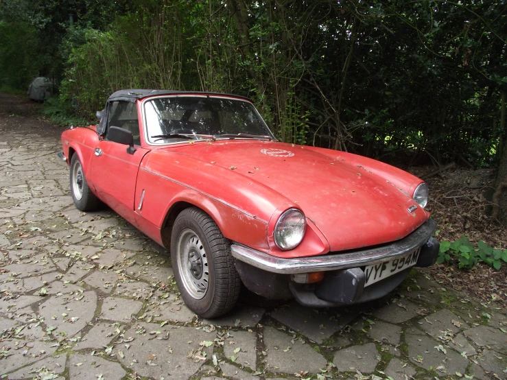 an old red car is parked on the street