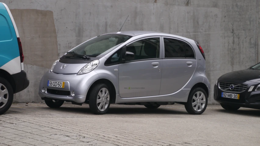 a silver smart car parked next to a blue van