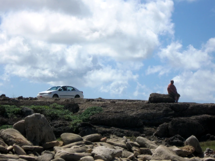 a man sitting on the rocks near a car