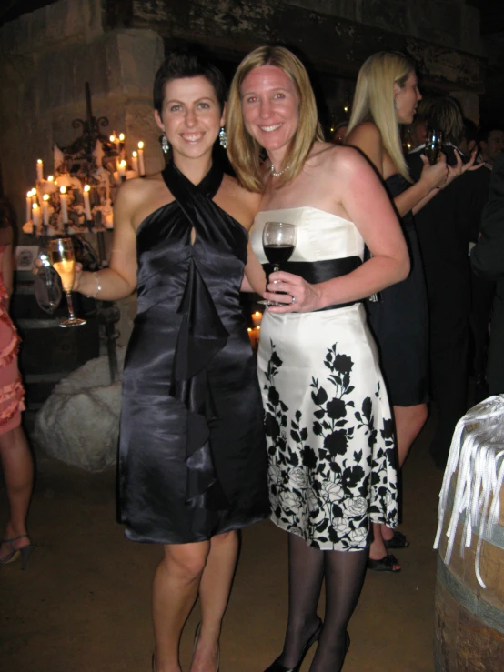 two women smiling and standing next to each other at a party