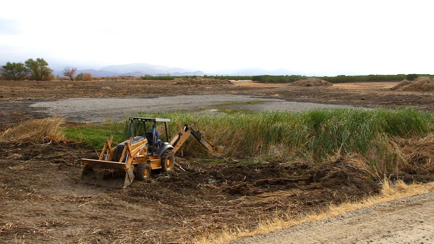 a tractor digging dirt in the middle of the grass