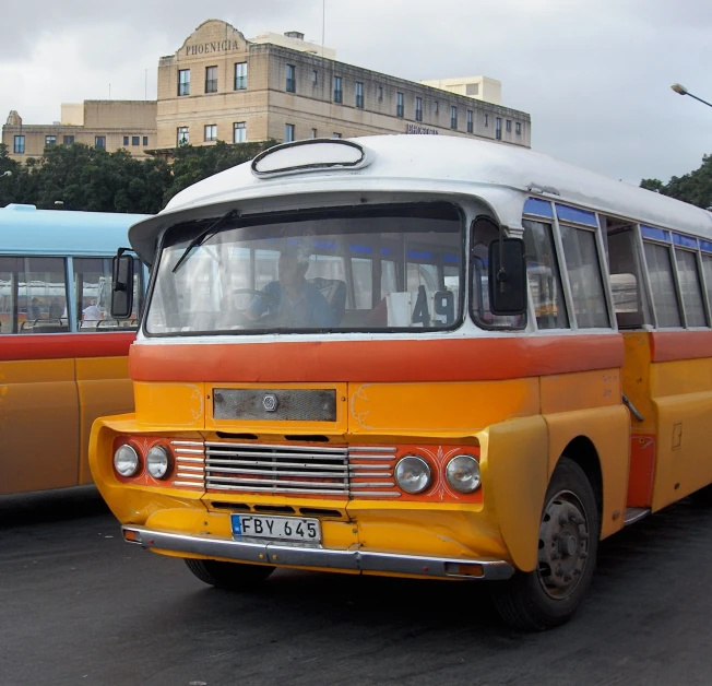 an orange and white bus is next to other buses