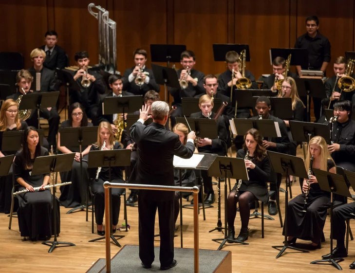 orchestra with conductor in dark jacket and white hair