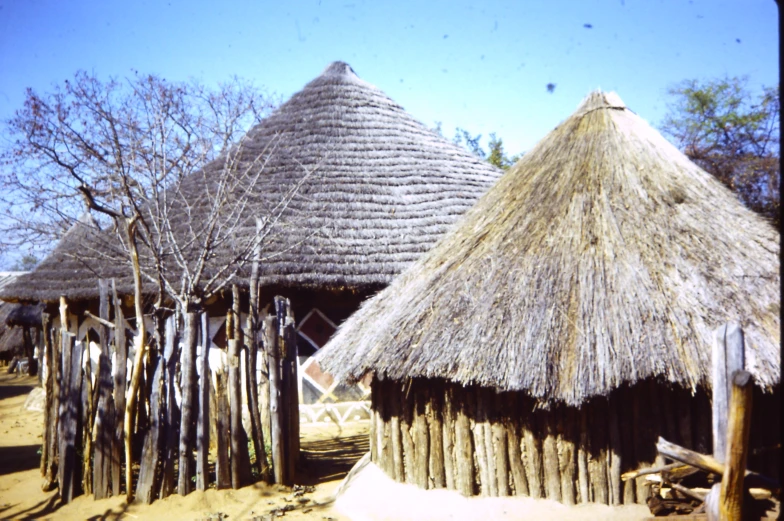 two thatched huts with a small group of people walking by